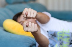 Teenager boy lying on sofa at home showing fig to parents at camera. Teen rudeness and protest. royalty free stock photos Teenager boy lying on sofa at home showing fig to parents at camera. Teen rudeness and protest. royalty free stock photos