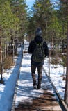 Teenager boy walking in forest with action camera on his helmet. Military backpack and pants. Wooden road in snowy royalty free stock image Teenager boy walking in forest with action camera on his helmet. Military backpack and pants. Wooden road in snowy royalty free stock image