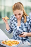 Teenager eating pizza looking in phone royalty free stock photo Teenager eating pizza looking in phone royalty free stock photo