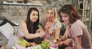 Teenager ladies multi ethnic at home in the bedroom eating lollipops and have a sweets party time in pajamas. stock video footage Teenager ladies multi ethnic at home in the bedroom eating lollipops and have a sweets party time in pajamas. stock video footage