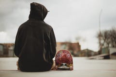 Teenager Sitting In A Black Sweatshirt Holding A Skateboard On A Slum Background Urban Stock Photography