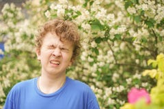 Teenager With Allergies Standing In A Blue T-shirt Among The Jasmine Bushes And Suffers From Bad Health Royalty Free Stock Image Teenager With Allergies Standing In A Blue T-shirt Among The Jasmine Bushes And Suffers From Bad Health Royalty Free Stock Image