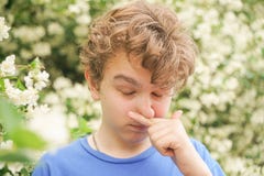 Teenager With Allergies Standing In A Blue T-shirt Among The Jasmine Bushes And Suffers From Bad Health Royalty Free Stock Photos Teenager With Allergies Standing In A Blue T-shirt Among The Jasmine Bushes And Suffers From Bad Health Royalty Free Stock Photos
