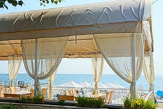 Teil der weißen Veranda des Restaurants mit Vorhängen und Möbeln auf dem Hintergrund des Meeres lizenzfreies stockfoto Teil der weißen Veranda des Restaurants mit Vorhängen und Möbeln auf dem Hintergrund des Meeres lizenzfreies stockfoto