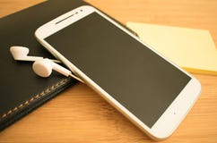 Telefone e fones de ouvido brancos na tabela imagem de stock Telefone e fones de ouvido brancos na tabela imagem de stock