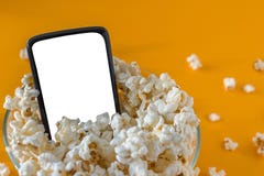 Telefono cellulare e popcorn in una ciotola, su una tavola gialla, primo piano Concetto di tecnologia fotografia stock Telefono cellulare e popcorn in una ciotola, su una tavola gialla, primo piano Concetto di tecnologia fotografia stock