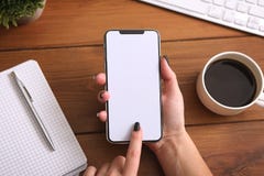 Telefono della tenuta della donna di affari con lo schermo vuoto bianco al posto di lavoro Vista superiore fotografie stock Telefono della tenuta della donna di affari con lo schermo vuoto bianco al posto di lavoro Vista superiore fotografie stock