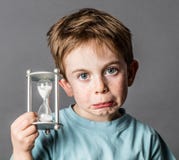 Teleurgestelde jonge jongen met een zandloper voor tijdconcept stock afbeelding Teleurgestelde jonge jongen met een zandloper voor tijdconcept stock afbeelding