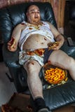Televisione mangiatrice di uomini grassa di sorveglianza e degli alimenti industriali immagini stock libere da diritti Televisione mangiatrice di uomini grassa di sorveglianza e degli alimenti industriali immagini stock libere da diritti