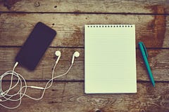 Teléfono celular, auriculares, cuaderno y pluma en la tabla de madera vieja Imagen de archivo libre de regalías Teléfono celular, auriculares, cuaderno y pluma en la tabla de madera vieja Imagen de archivo libre de regalías