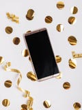 Teléfono con la pantalla en blanco que miente en la tabla con la decoración y la malla de oro del color fotografía de archivo libre de regalías Teléfono con la pantalla en blanco que miente en la tabla con la decoración y la malla de oro del color fotografía de archivo libre de regalías