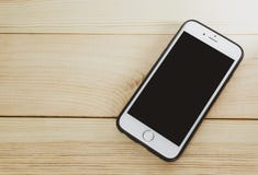 Teléfono móvil con la pantalla en blanco en de madera foto de archivo Teléfono móvil con la pantalla en blanco en de madera foto de archivo
