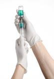 Tema médico: la mano del doctor en un guante blanco que sostiene un frasco azul de líquido para la inyección aislada en el fondo fotografía de archivo libre de regalías Tema médico: la mano del doctor en un guante blanco que sostiene un frasco azul de líquido para la inyección aislada en el fondo fotografía de archivo libre de regalías