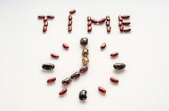 Tempo di parola e fronte di orologio a forma di dai fagioli variopinti su fondo bianco Concetto sano di cibo fotografia stock Tempo di parola e fronte di orologio a forma di dai fagioli variopinti su fondo bianco Concetto sano di cibo fotografia stock