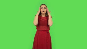Tender girl in red dress is cooling herself by her hand, suffering from high temperature weather. Green screen