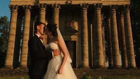 Tenderly φιλώντας ζεύγος των ελκυστικών ευτυχών newlyweds πέρα από το υπόβαθρο του παλαιού μπαρόκ κτηρίου ύφους κατά τη διάρκεια απόθεμα βίντεο Tenderly φιλώντας ζεύγος των ελκυστικών ευτυχών newlyweds πέρα από το υπόβαθρο του παλαιού μπαρόκ κτηρίου ύφους κατά τη διάρκεια απόθεμα βίντεο