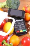 Terminal y smartphone con tecnología de NFC, frutas y verduras, el pagar cashless del pago hacer compras foto de archivo Terminal y smartphone con tecnología de NFC, frutas y verduras, el pagar cashless del pago hacer compras foto de archivo