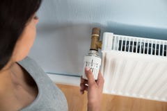 Termostato de giro da jovem mulher no radiador imagens de stock Termostato de giro da jovem mulher no radiador imagens de stock