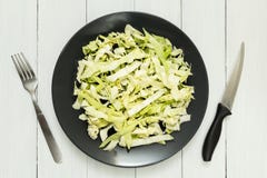 Testa di cavolo organico fresco su un piatto, su un coltello e su una forcella Tabella di legno bianca immagini stock Testa di cavolo organico fresco su un piatto, su un coltello e su una forcella Tabella di legno bianca immagini stock