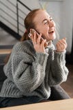 Testarossa di risata che si siede sullo strato che ha una conversazione sul telefono a casa fotografie stock libere da diritti Testarossa di risata che si siede sullo strato che ha una conversazione sul telefono a casa fotografie stock libere da diritti