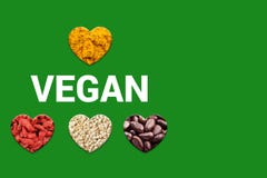 Testo e cuori del vegano con i punti del cacao, i grani bianchi della quinoa, le bacche secche di goji e la curcuma immagine stock libera da diritti Testo e cuori del vegano con i punti del cacao, i grani bianchi della quinoa, le bacche secche di goji e la curcuma immagine stock libera da diritti