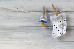 Tettarella e calzini del bambino che appendono sulla corda da bucato su fondo di legno fotografie stock libere da diritti Tettarella e calzini del bambino che appendono sulla corda da bucato su fondo di legno fotografie stock libere da diritti