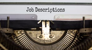 Text `Job Descriptions` typed on retro typewriter. Business concept
