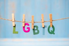 Texte du plan rapproché LGBTQ, pour lesbien, gai, bisexuel, le transsexuel, et accrocher sur la ligne avec le fond en bois bleu photographie stock Texte du plan rapproché LGBTQ, pour lesbien, gai, bisexuel, le transsexuel, et accrocher sur la ligne avec le fond en bois bleu photographie stock