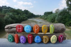 Texto do feliz aniversario com as pedras coloridas sobre duas partes de madeira e o fundo natural fotos de stock Texto do feliz aniversario com as pedras coloridas sobre duas partes de madeira e o fundo natural fotos de stock