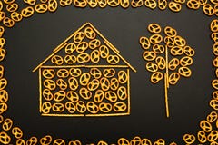 Textura do fundo de pretzeis salgados e de mini varas na forma de uma casa e de uma árvore em um fundo preto fotos de stock Textura do fundo de pretzeis salgados e de mini varas na forma de uma casa e de uma árvore em um fundo preto fotos de stock