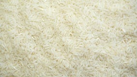 Texture of uncooked white rice grains on a rotating background