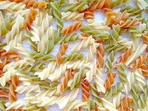 Textured Italian food background - colorful uncooked fusilli pasta on wooden table stock image Textured Italian food background - colorful uncooked fusilli pasta on wooden table stock image