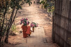Thai Monk With Lotus Flowers In His Hands And Traditional Broom Stock Photo