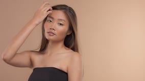 Thais Aziatisch model met natuurlijke make-up op beige achtergrond stock video Thais Aziatisch model met natuurlijke make-up op beige achtergrond stock video