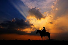 The Silhouette Of A Cowboy On Horseback At Sunset On  Background Stock Photos