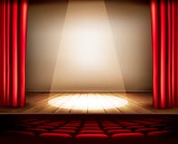 A theater stage with a red curtain, seats and a spotlight.
