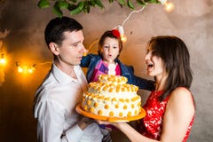 Theme family holiday childrens birthday and blowing out candles on large cake. young family of three people standing and holding 5 royalty free stock image Theme family holiday childrens birthday and blowing out candles on large cake. young family of three people standing and holding 5 royalty free stock image