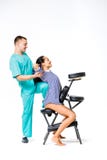 Theme massage and office. young male therapist in blue suit doing back massage with his knee braced in the spine of female worker, Royalty Free Stock Photos Theme massage and office. young male therapist in blue suit doing back massage with his knee braced in the spine of female worker, Royalty Free Stock Photos