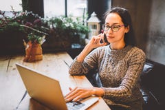 Theme is small business. A young freelance woman working behind a laptop computer in a coffee shop decorated with Christmas decor Royalty Free Stock Photos Theme is small business. A young freelance woman working behind a laptop computer in a coffee shop decorated with Christmas decor Royalty Free Stock Photos