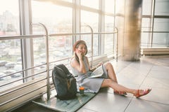 Theme of tourism and travel of young student. Beautiful young caucasian girl in dress and hat sits on floor tourist rug inside stock photography Theme of tourism and travel of young student. Beautiful young caucasian girl in dress and hat sits on floor tourist rug inside stock photography