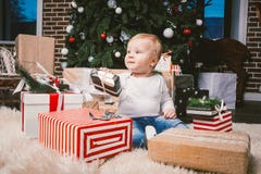 Theme winter and Christmas holidays. Child boy Caucasian blond 1 year old sitting home floor near Christmas tree with New Year dec royalty free stock images Theme winter and Christmas holidays. Child boy Caucasian blond 1 year old sitting home floor near Christmas tree with New Year dec royalty free stock images