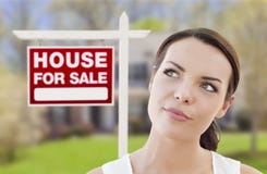 Thinking Woman In Front Of House And For Sale Sign Stock Photography