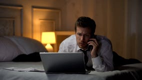 Thoughtful male typing on laptop and talking on phone preparing report, deadline stock photography Thoughtful male typing on laptop and talking on phone preparing report, deadline stock photography