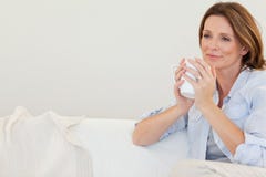 Thoughtful woman with cup of coffee on sofa Stock Photo Thoughtful woman with cup of coffee on sofa Stock Photo