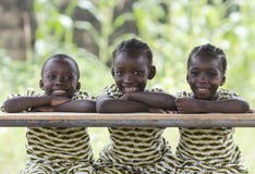 Three African children sitting outdoors smiling and laughing royalty free stock images Three African children sitting outdoors smiling and laughing royalty free stock images