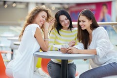 Three beautiful stylish girls sit at a table in a cafe in the modern mall and chat after shopping royalty free stock photos Three beautiful stylish girls sit at a table in a cafe in the modern mall and chat after shopping royalty free stock photos