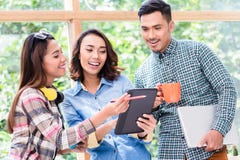 Three cheerful young employees working together on a project stock images Three cheerful young employees working together on a project stock images