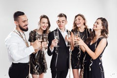 Three girls and two guys dressed in stylish elegant clothes stand together and clink glasses with champagne on the white royalty free stock photo Three girls and two guys dressed in stylish elegant clothes stand together and clink glasses with champagne on the white royalty free stock photo