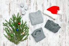 Three gray sweaters, Santa`s hat and fir branch on a wooden back stock photography Three gray sweaters, Santa`s hat and fir branch on a wooden back stock photography