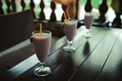 Three jars of pink berry milkshakes with straws on old wooden table. stock photos Three jars of pink berry milkshakes with straws on old wooden table. stock photos